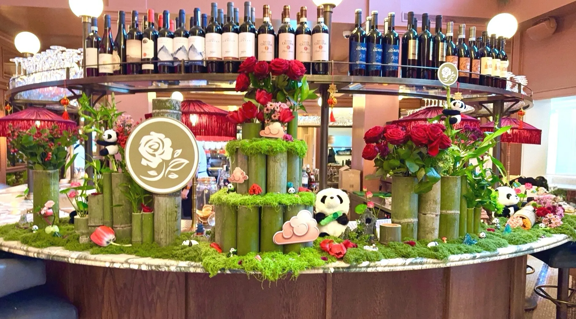 A round bar dressed with bamboo, moss, red roses, toy pandas and the Bicester Village rose emblem