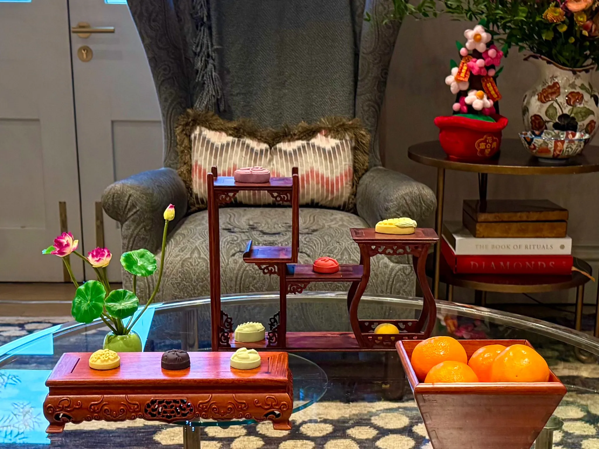 Traditional rosewood display stands with festive cakes, mandarins and blossom on a lounge table