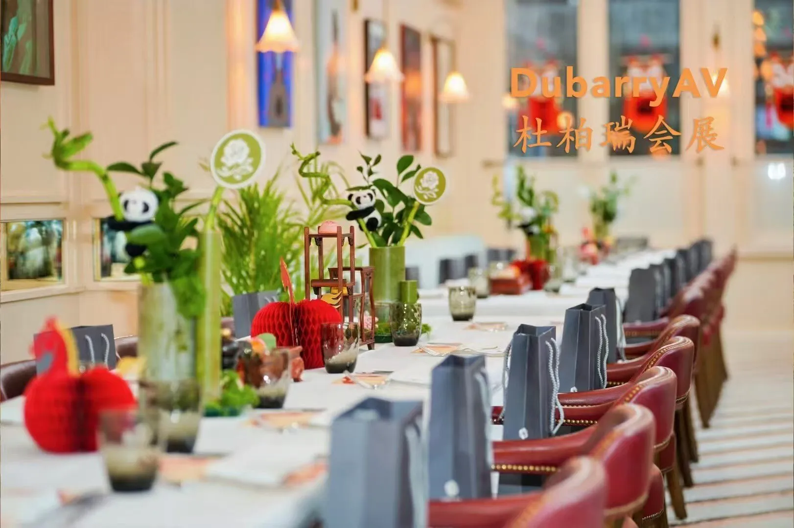 A long dining table set with bamboo and panda centrepieces, red paper decorations and a gift bag at every place