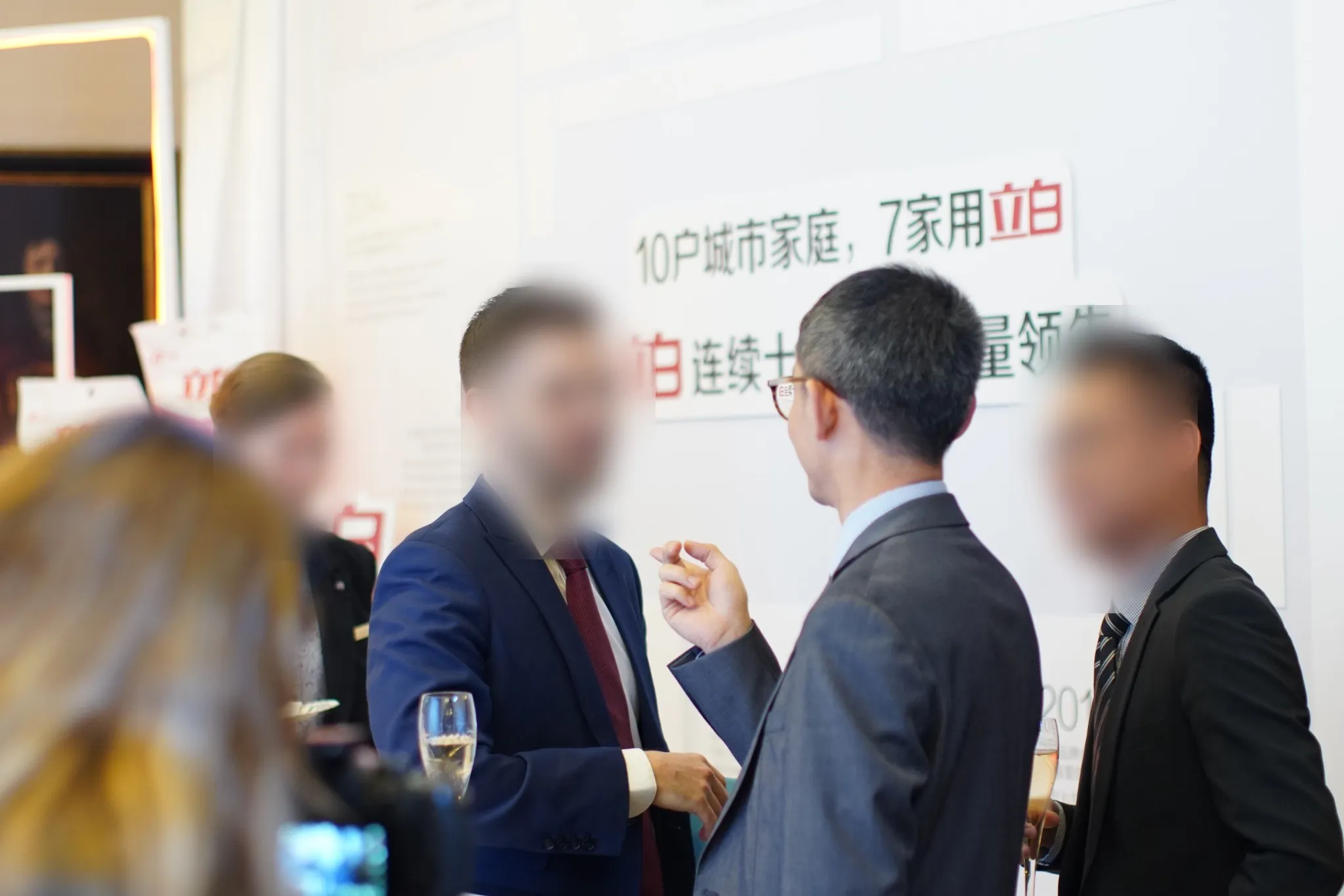 Guests in conversation with drinks in front of the brand wall