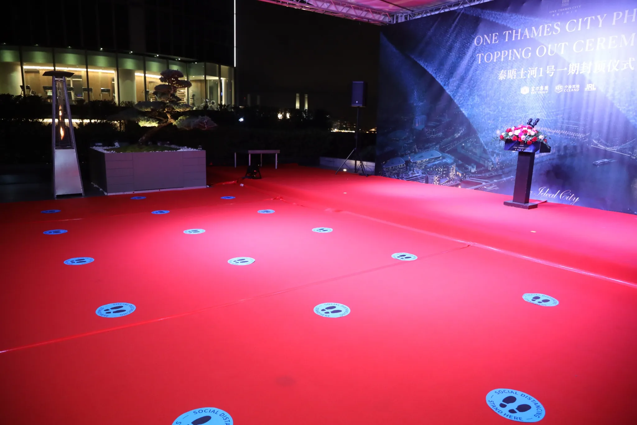 The ceremony stage at night, lit in red, with social distancing markers set out across the carpet