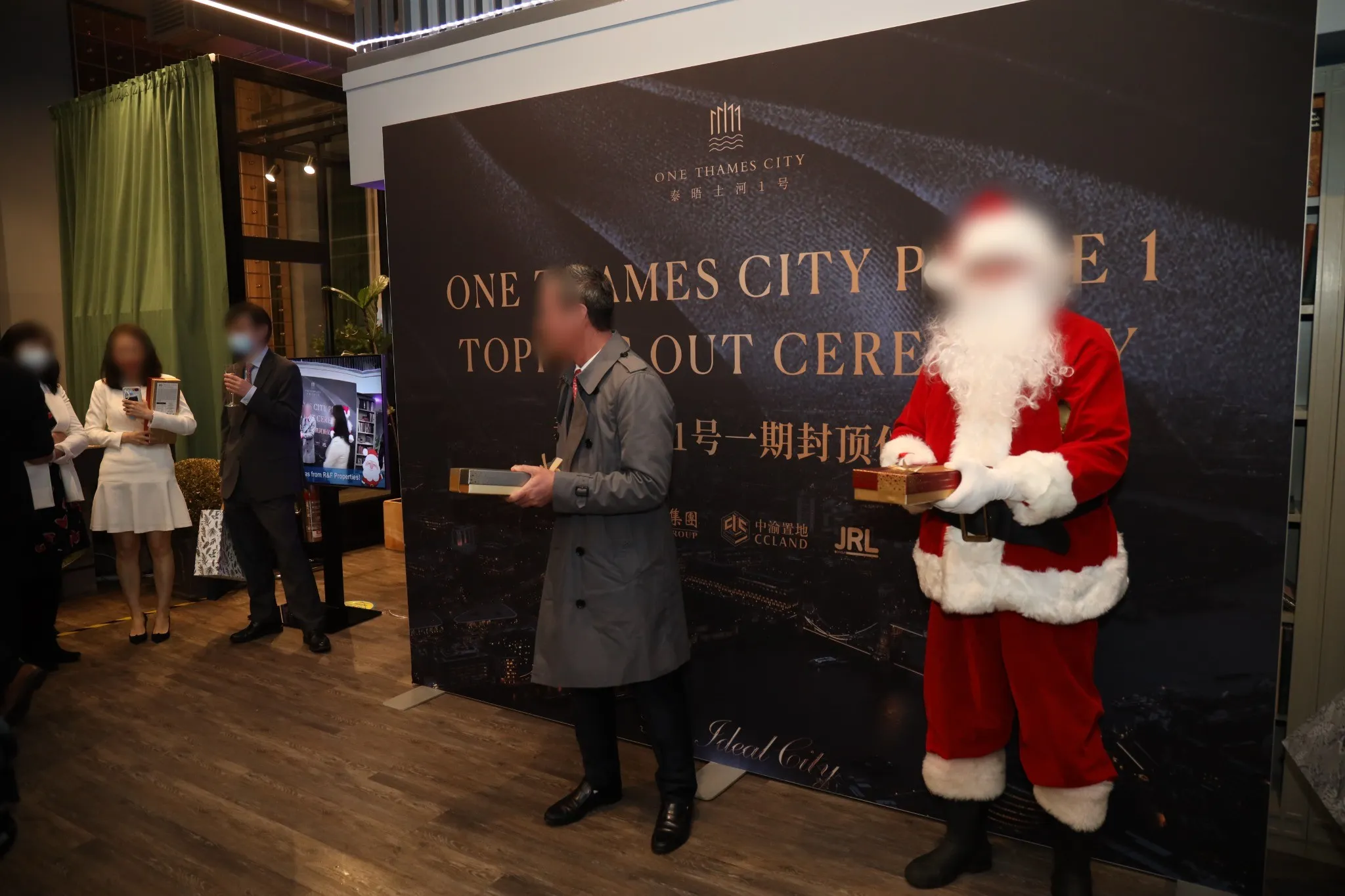 Guests in masks at the indoor reception, in front of the topping out ceremony backdrop