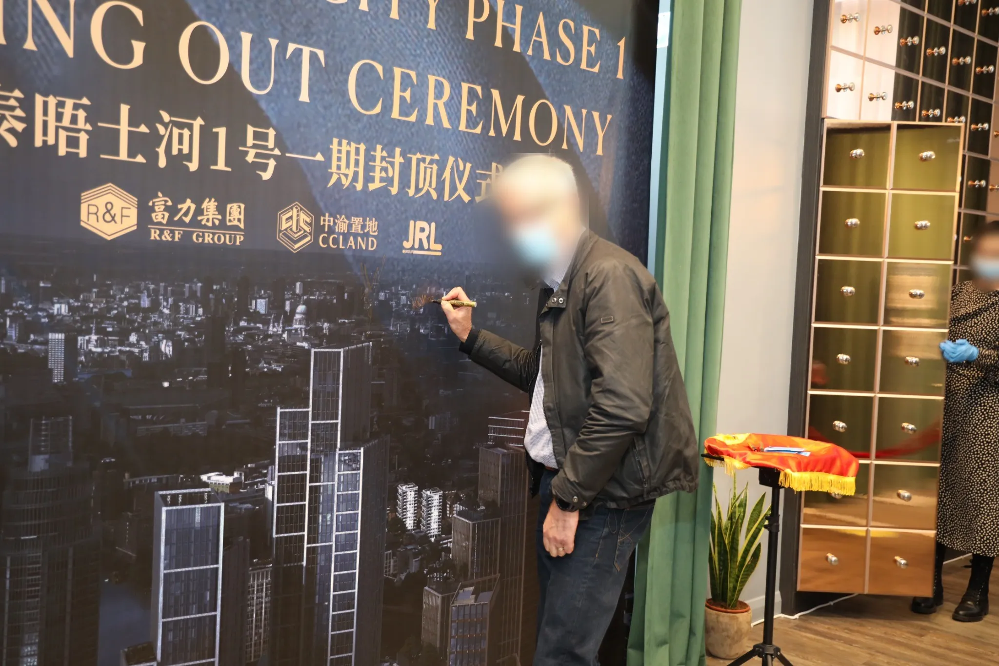 A guest signing the One Thames City topping out ceremony wall